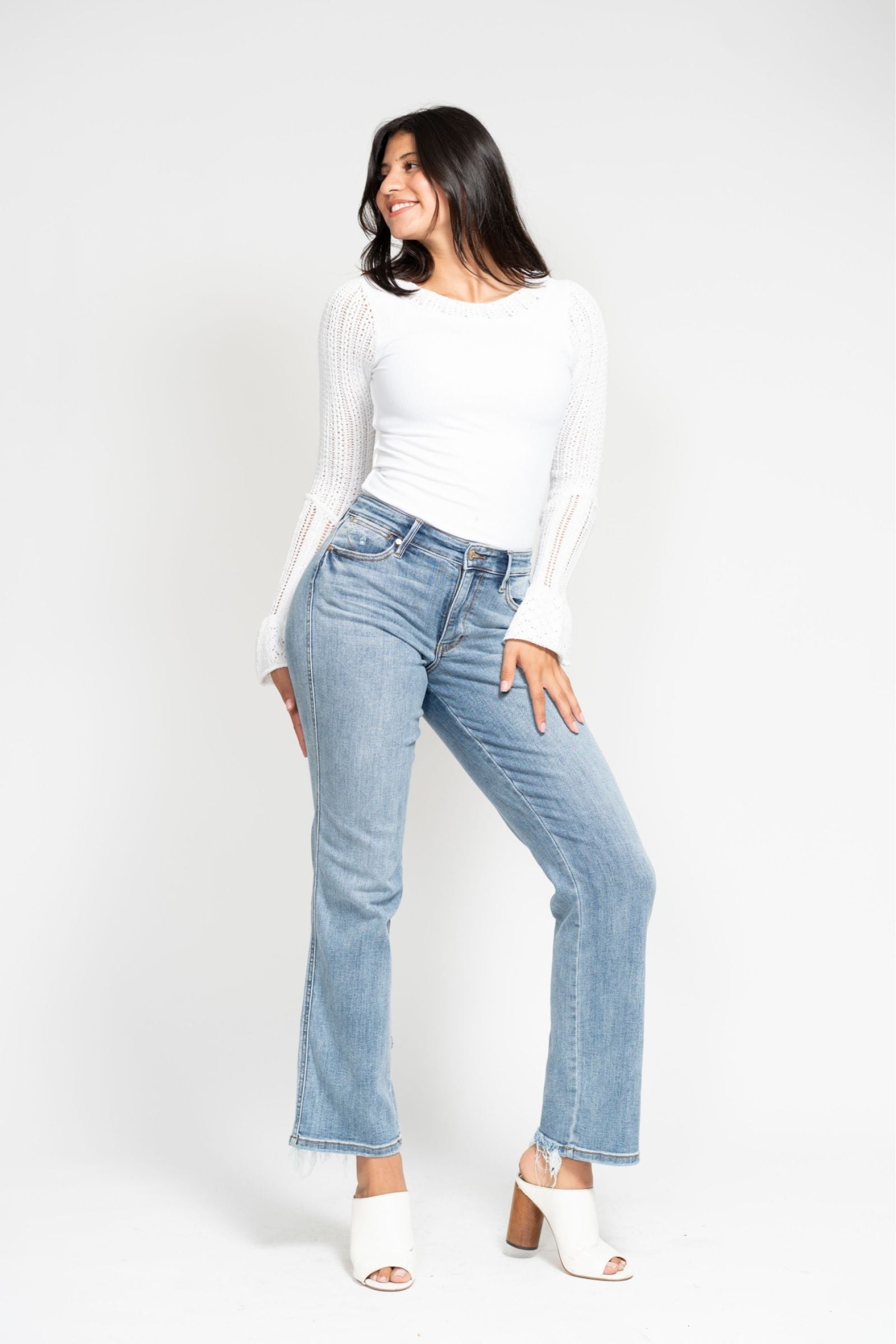 Woman wearing mid-rise Judy Blue Jeans 82540 with cell phone pocket, paired with white top and heels