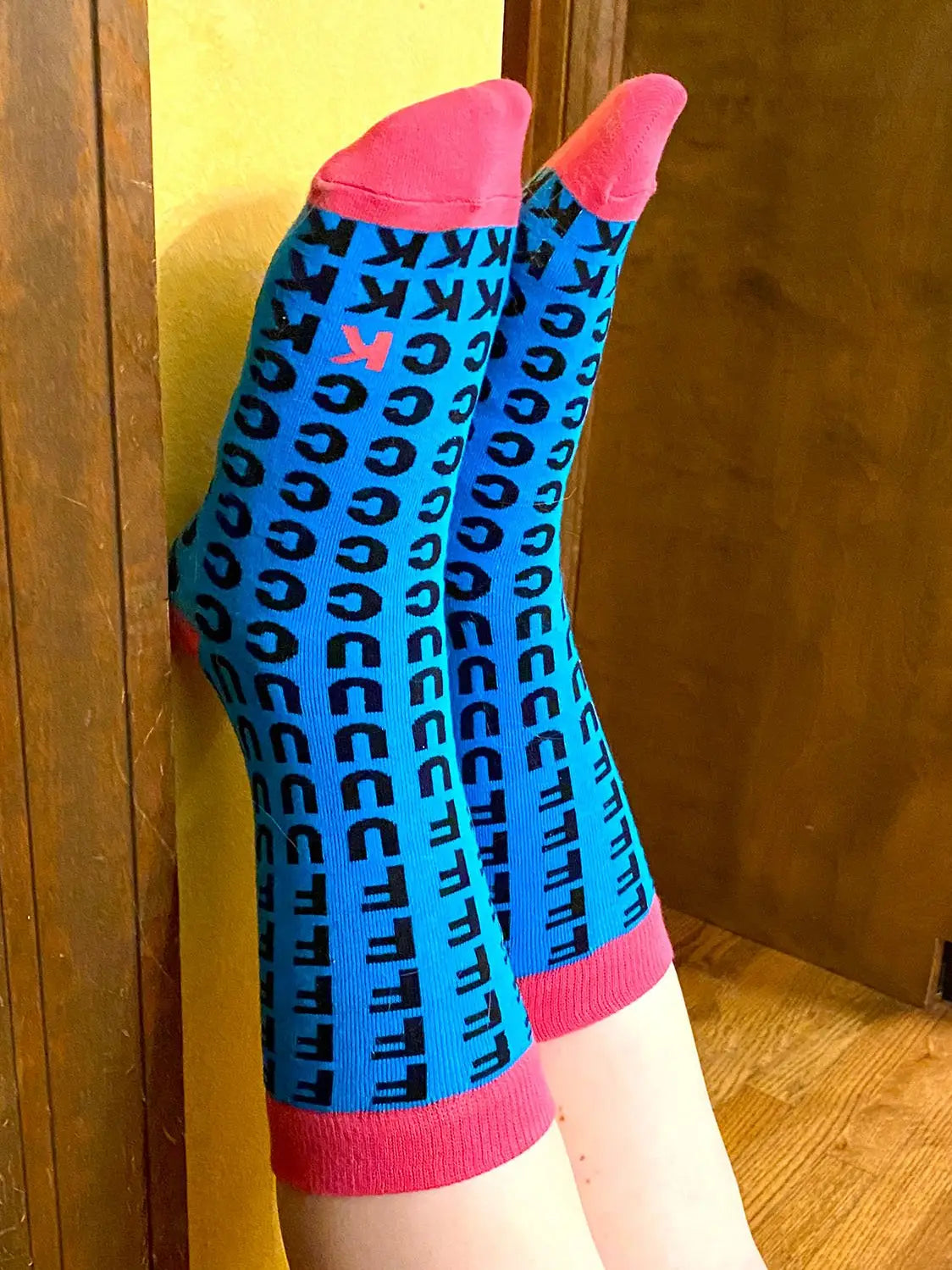 Blue women’s crew socks with bold black and pink letters and pink toes and cuffs
