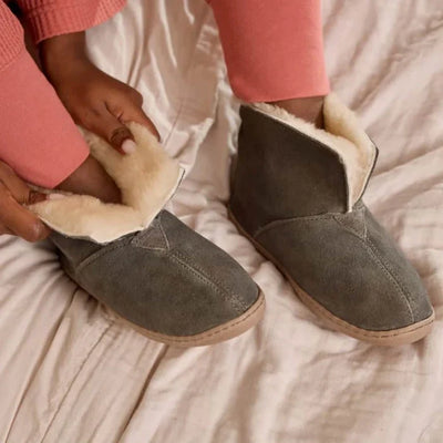 Pre Order Minnetonka Sheepskin Ankle Boot with fold-up collar and suede finish on bed.