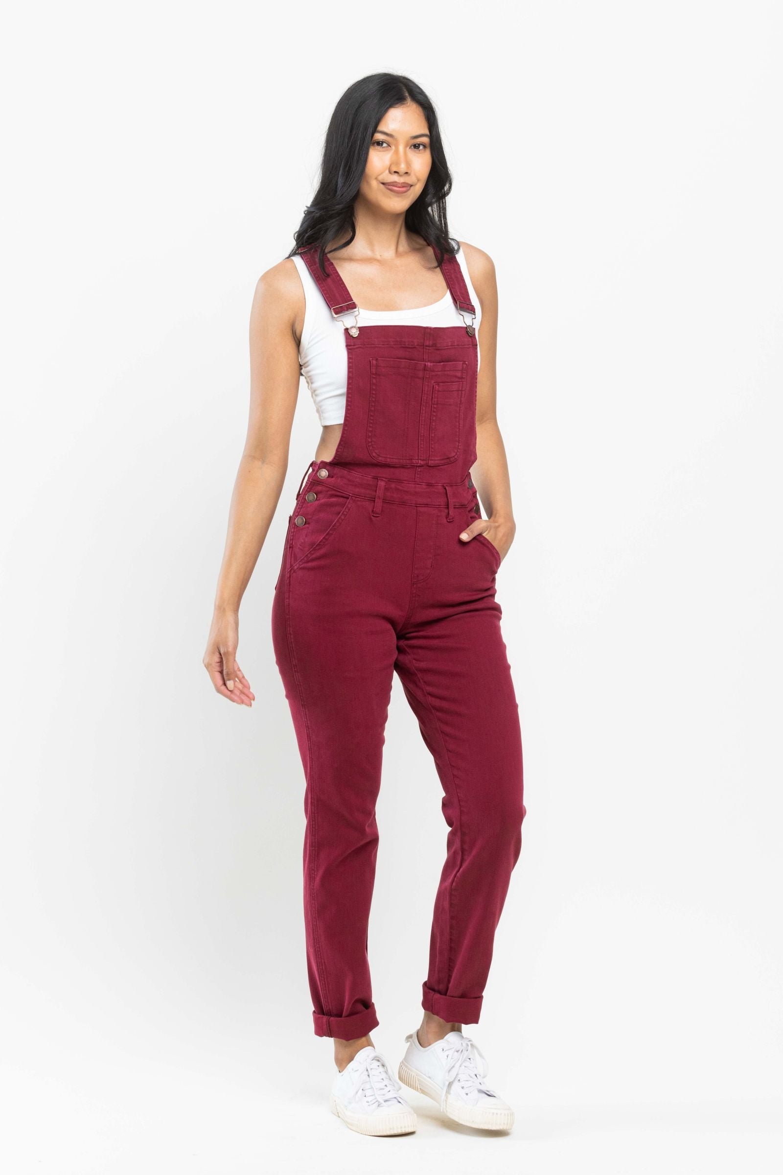 Woman wearing crimson Judy Blue Overalls 88712 boyfriend fit straight leg overalls with white sneakers