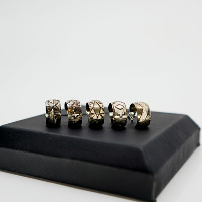 Handmade sterling silver stamped mini hoop earrings with unique designs displayed on black box