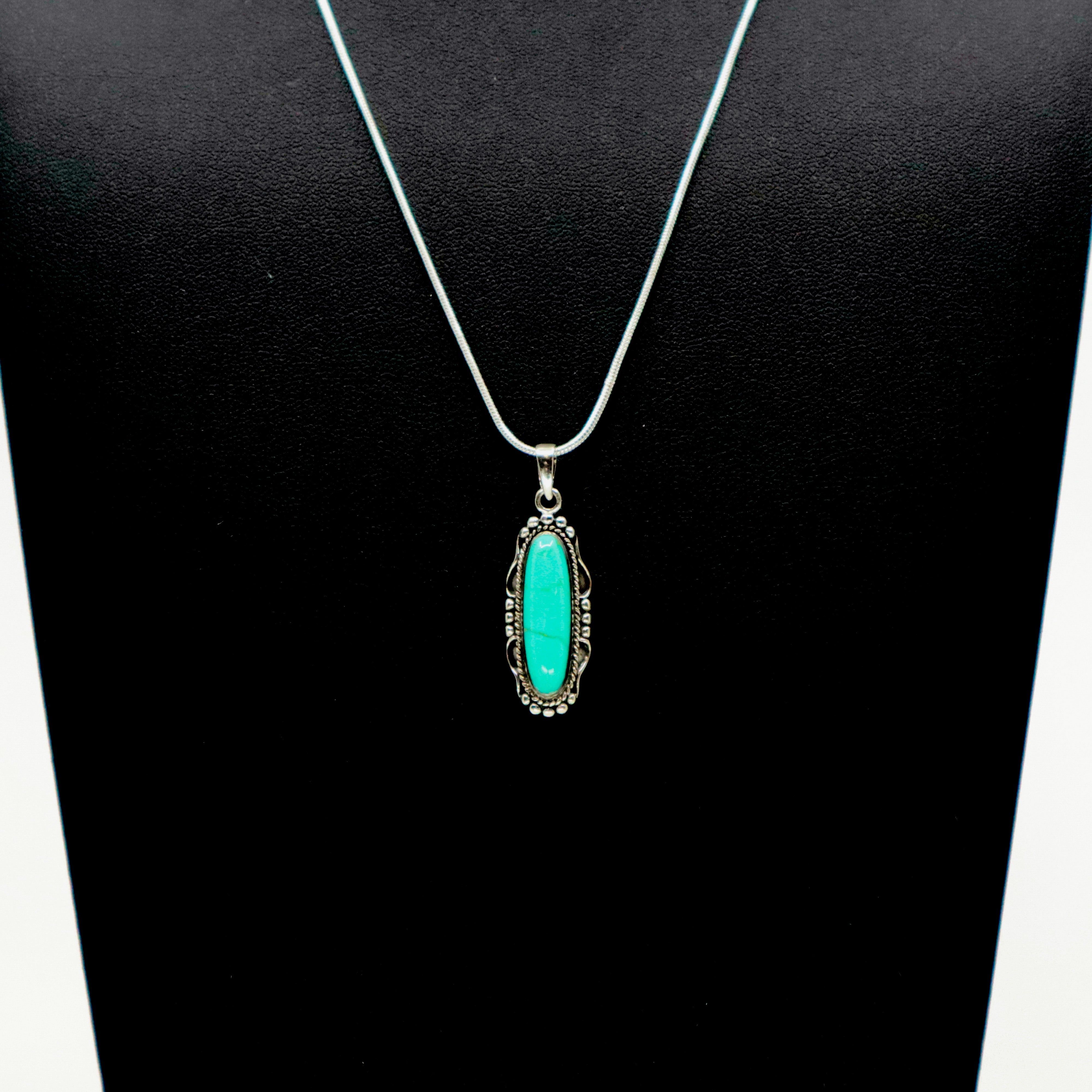 Sterling silver necklace with oval turquoise pendant on black display bust