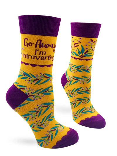 Yellow and purple women's crew socks with "Go Away I'm Introverting" text and leafy pattern, soft and stretchy.