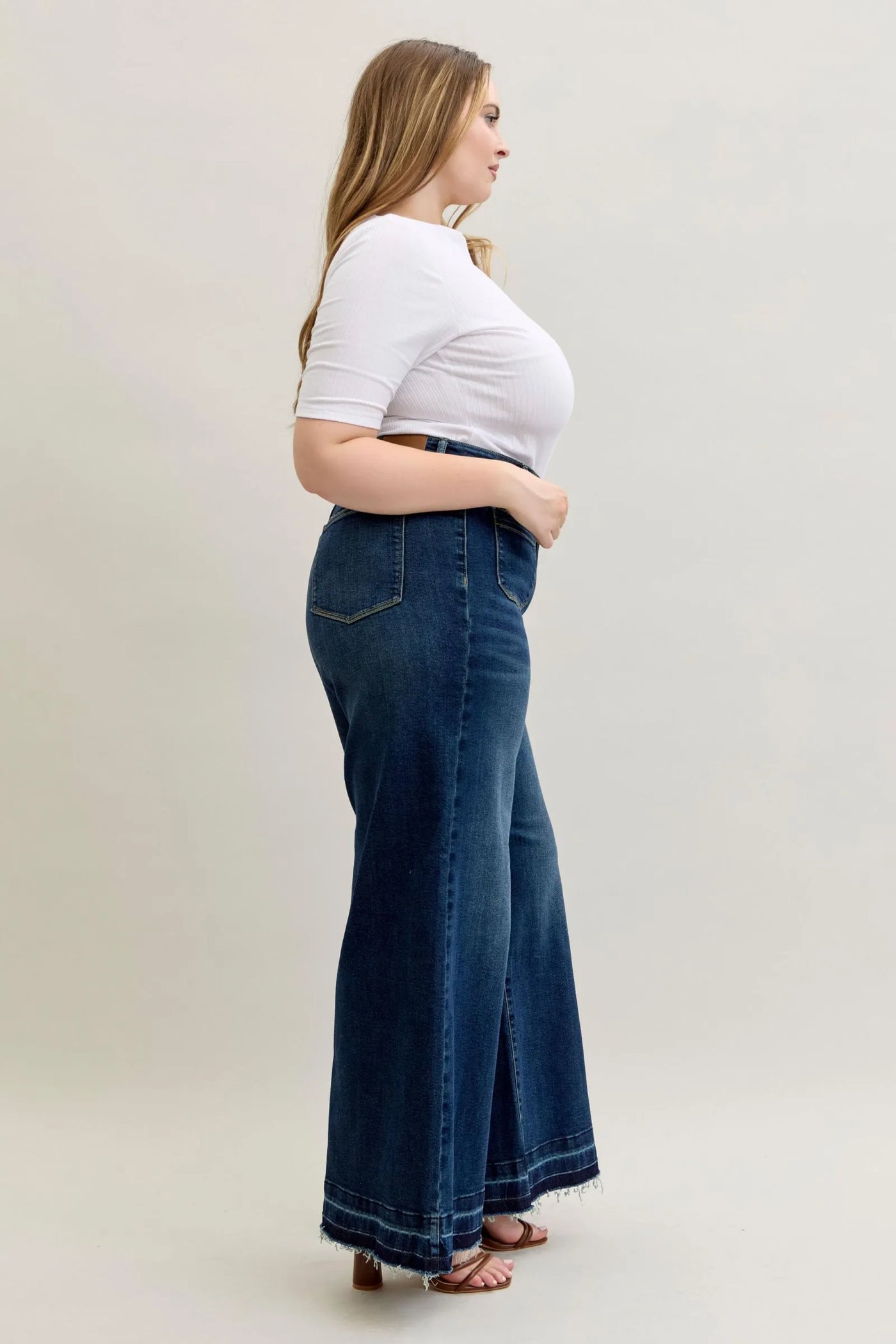 Plus size model wearing Judy Blue high waist palazzo jeans with a wide-leg cut and dark wash denim