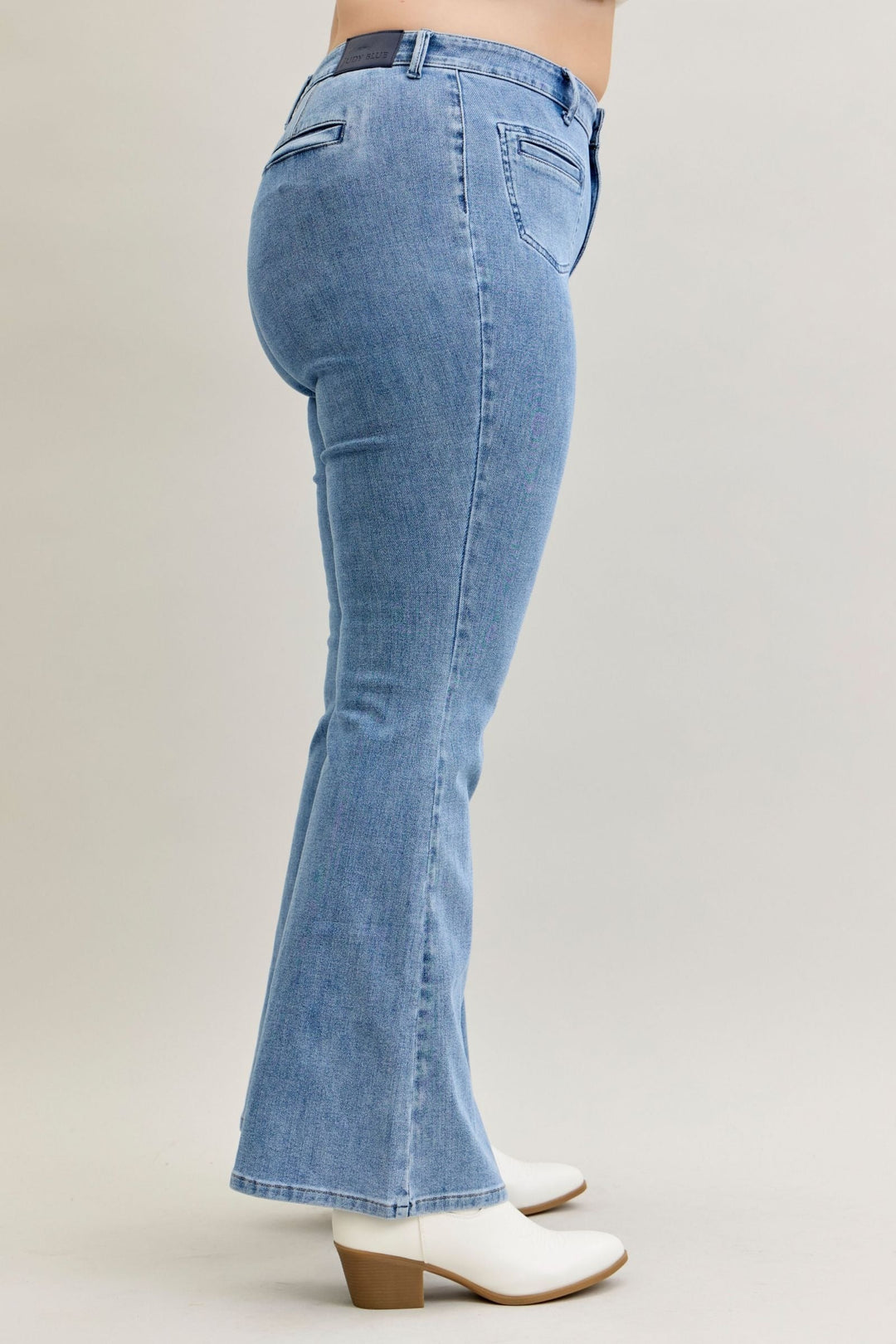Side view of high-rise flare Judy Blue Jeans in soft stretch denim with front patch and welt pockets, styled with white boots