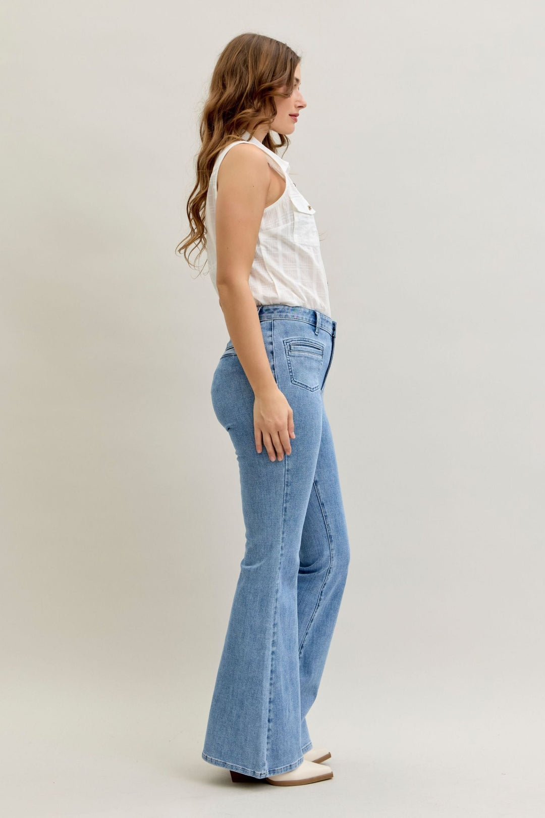 Side view of woman wearing high-rise flare Judy Blue Jeans in light blue stretch denim with front patch and welt pockets