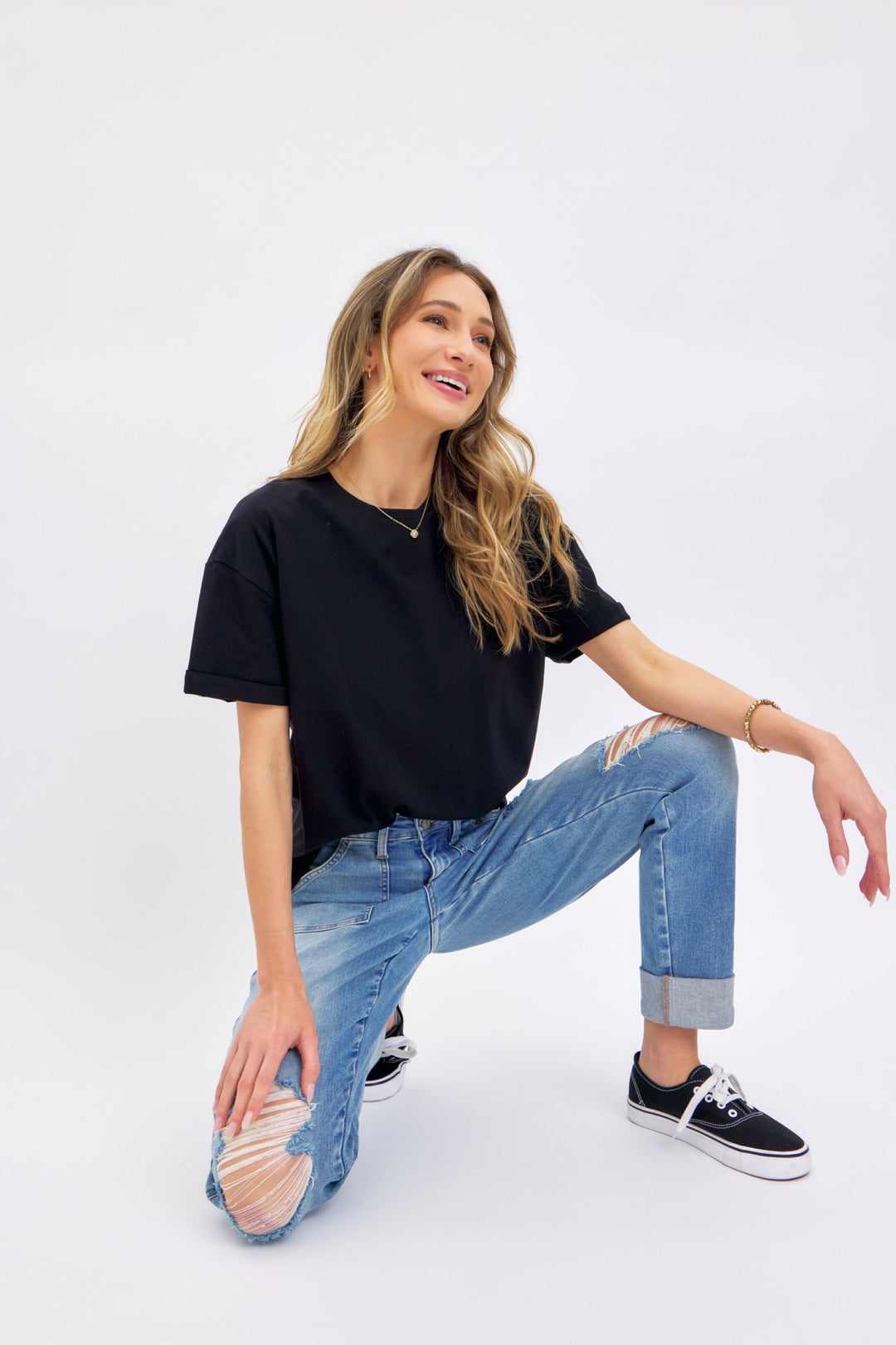 Woman wearing high-rise Judy Blue Jeans 88825 distressed cuffed boyfriend style with black t-shirt and sneakers
