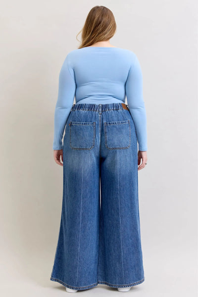 Back view of a woman wearing high waist featherweight palazzo jeans by Judy Blue Jeans with elastic waistband and wide-leg cut