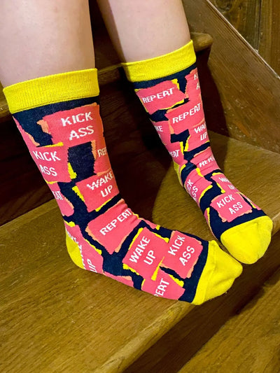 Women's crew socks with motivational "Wake Up Kick A** Repeat" design, yellow accents, cotton blend, fits shoe size 5-10