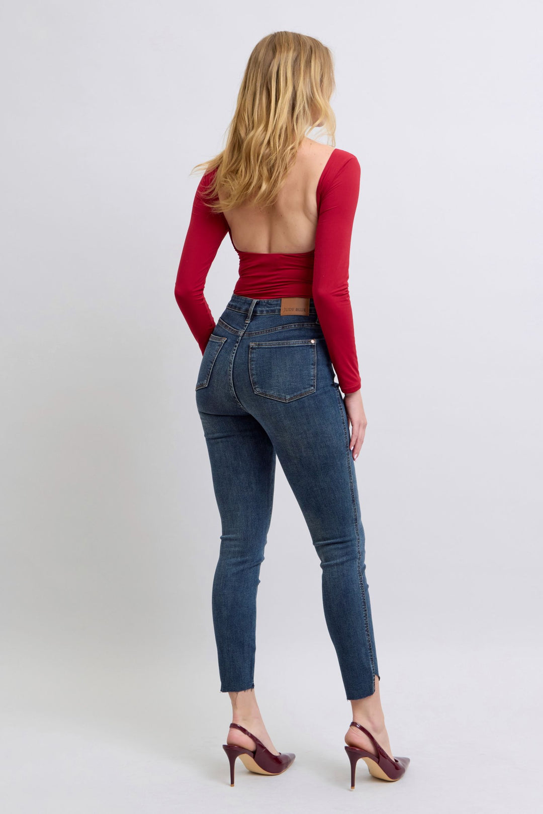 woman wearing high waist Judy Blue Jeans 88913 skinny jeans with step hem and red open-back top