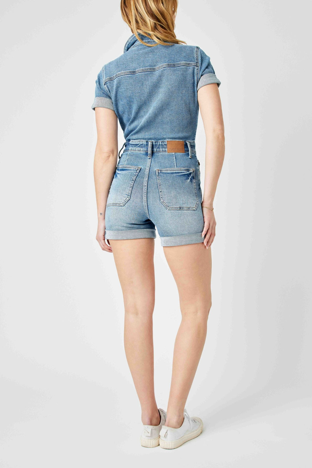 Woman wearing high waisted short sleeve Judy Blue Overalls denim romper from the back