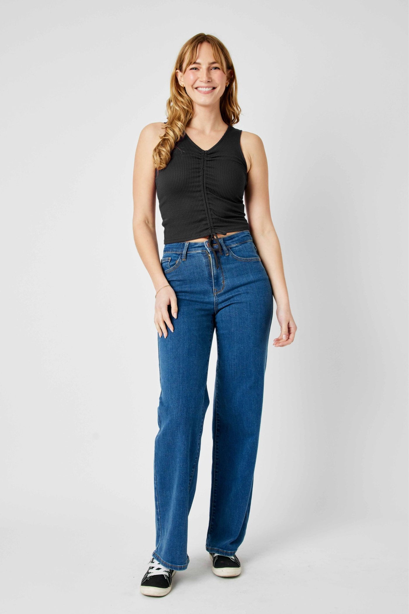 Woman wearing Judy Blue Jeans high waisted vintage wide leg jeans with black sleeveless top and sneakers