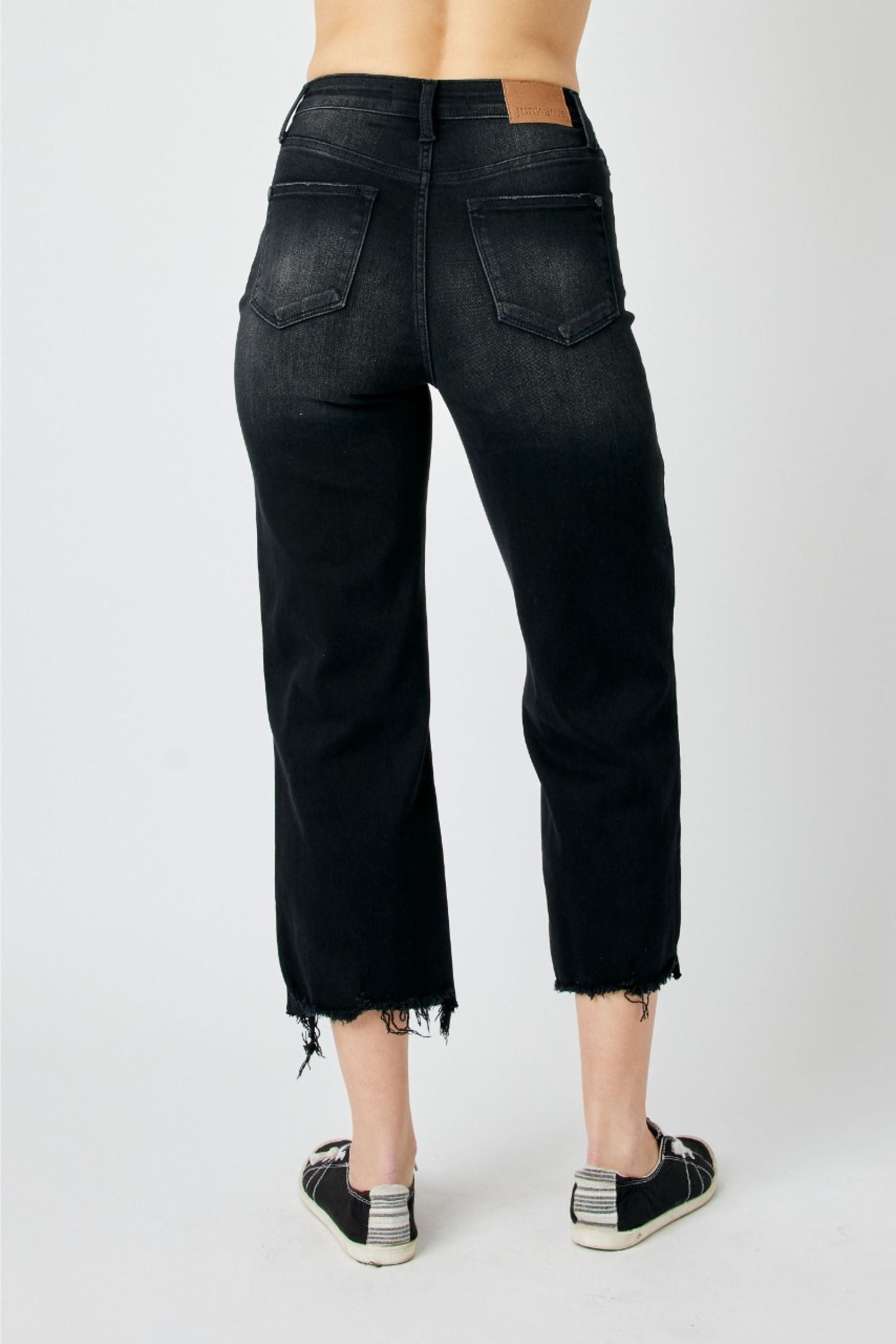 High-rise cropped black jeans with distressed design and raw hem detailing.