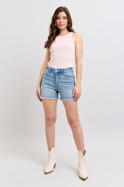 Judy Blue Shorts with high-rise cut and raw hem in light denim, modeled with white boots.