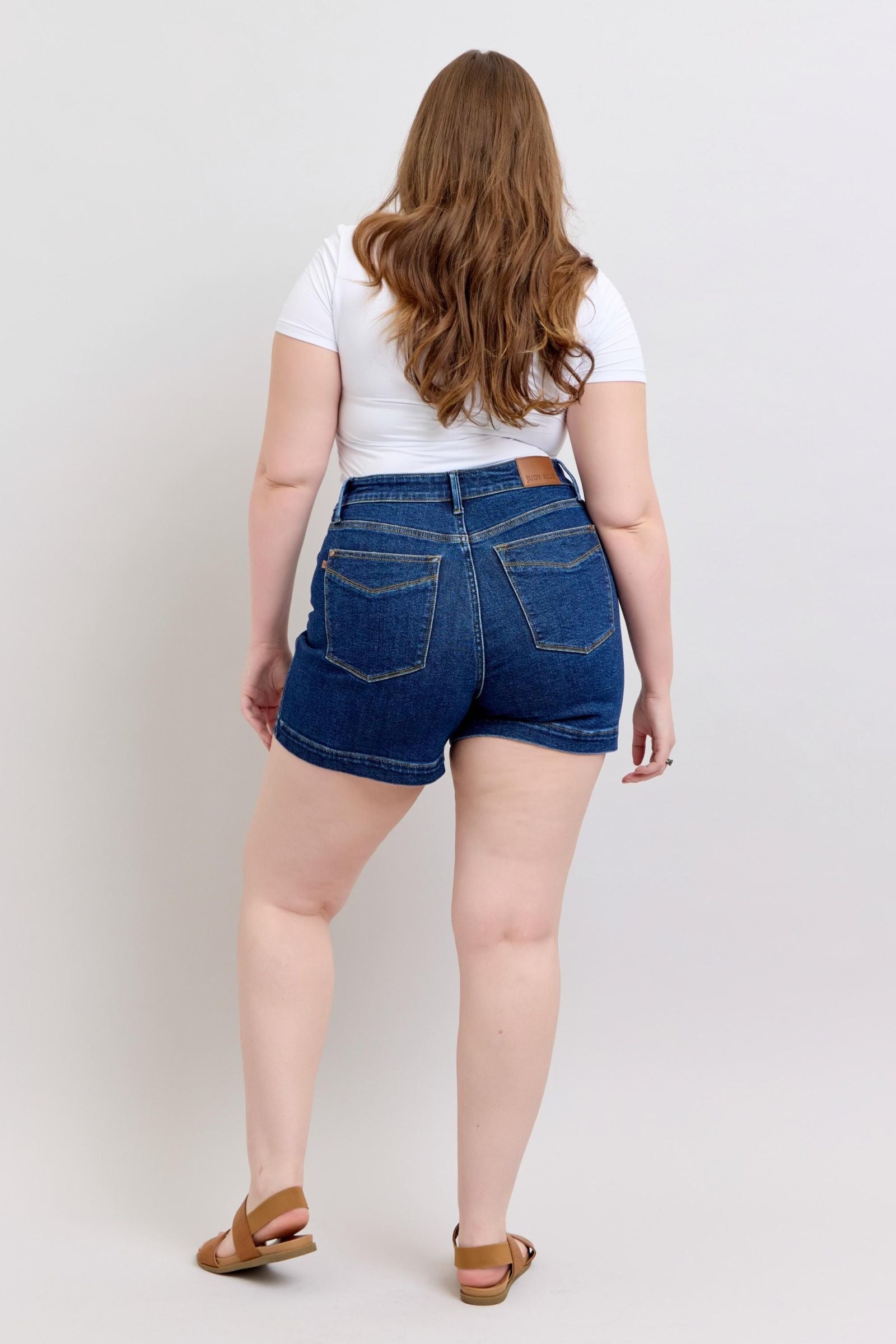 Plus size model wearing high waist Judy Blue Shorts 150333 in dark denim from the back