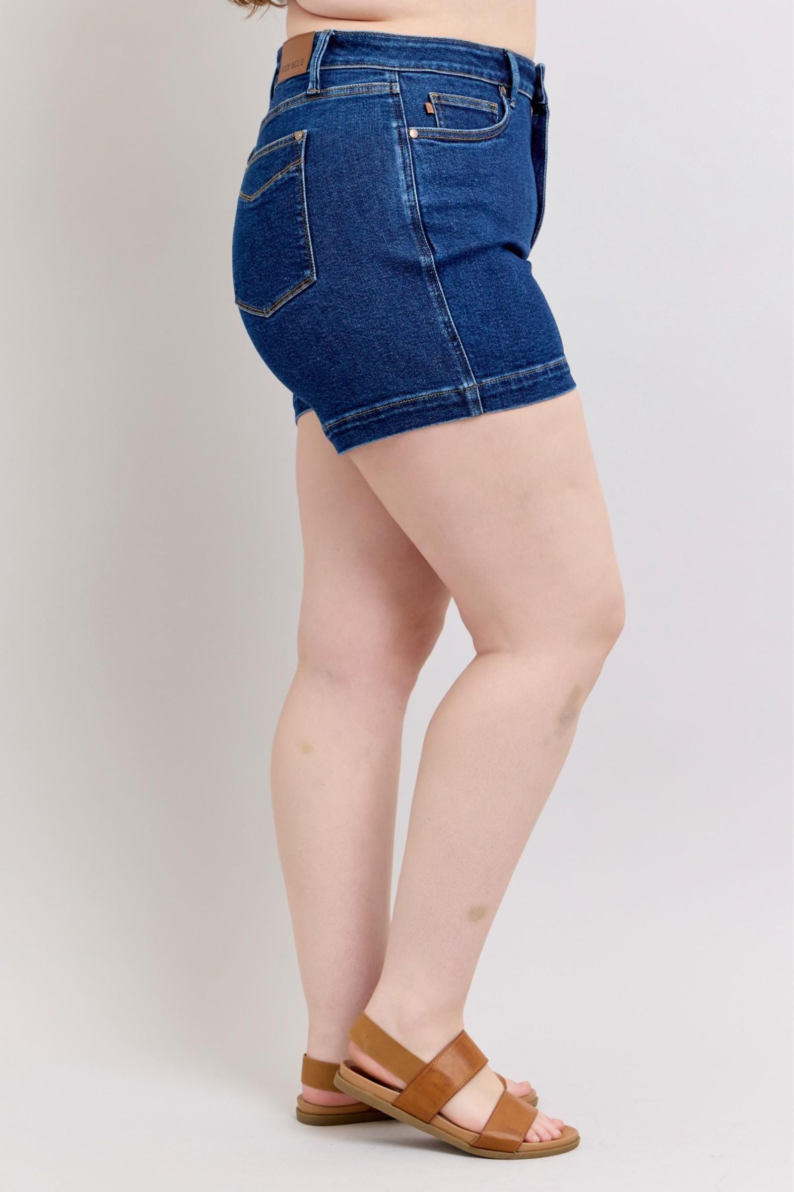 Plus size model wearing high waist Judy Blue Shorts 150333 with tummy control and 4.25-inch inseam in dark blue denim