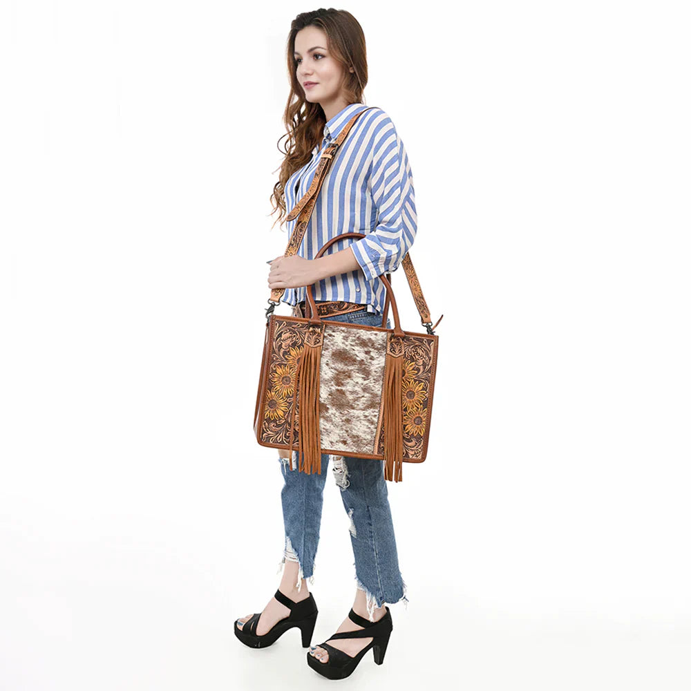 American Darling Tote Bag ADBG230TAWSUNF, handcrafted leather design, western style with fringes, cowhide embellishments, worn by model.