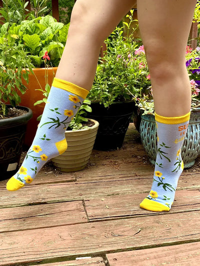 Women's crew socks with yellow buttercup flowers and yellow accents, bold "Suck It Up Buttercup" text design.