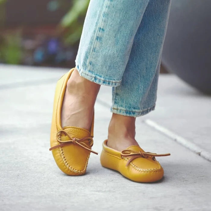 Women's yellow Double Deerskin Softsole moccasins with rawhide lace detail and rubber sole worn with jeans