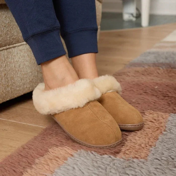 Minnetonka Sheepskin Mule slippers featuring suede and plush sheepskin lining, with soft cuff and durable rubber sole.