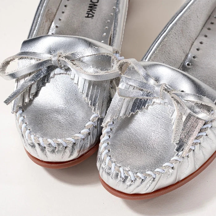 Minnetonka Kilty Hardsole Moccasins in silver suede with fringe and bow detailing.