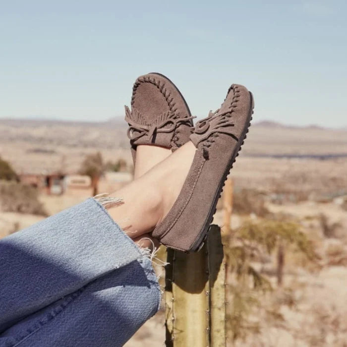 Minnetonka Kilty Hardsole moccasin in gray suede with intricate stitching and durable rubber sole.