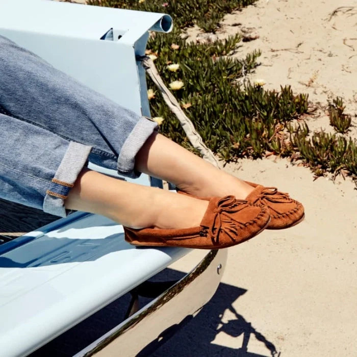 Minnetonka Kilty Hardsole moccasins in tan suede leather with intricate stitching and rubber sole.