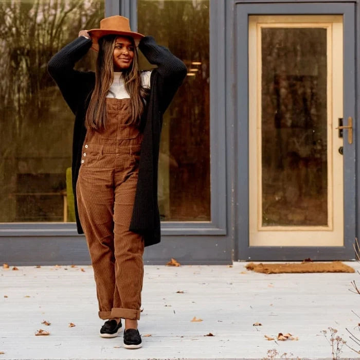 Woman wearing casual outfit with Minnetonka Discover Classic Shoes stands on patio.