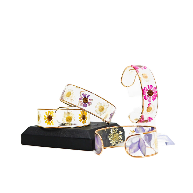 Set of dried flower resin cuff bracelets with colorful floral designs encased in clear resin