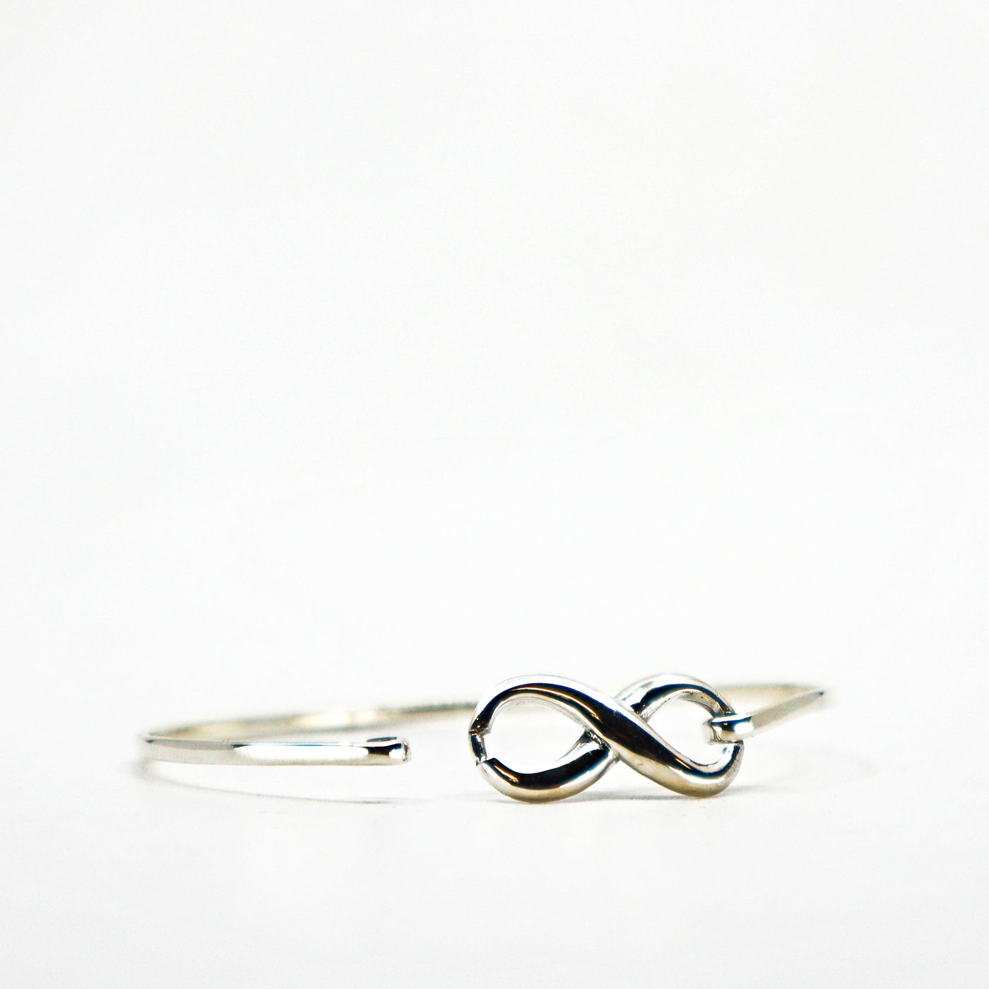 Sterling silver infinity cuff bracelet with sleek open design on white background