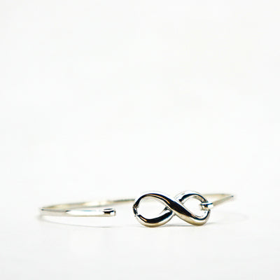 Sterling silver infinity cuff bracelet with sleek open design on white background