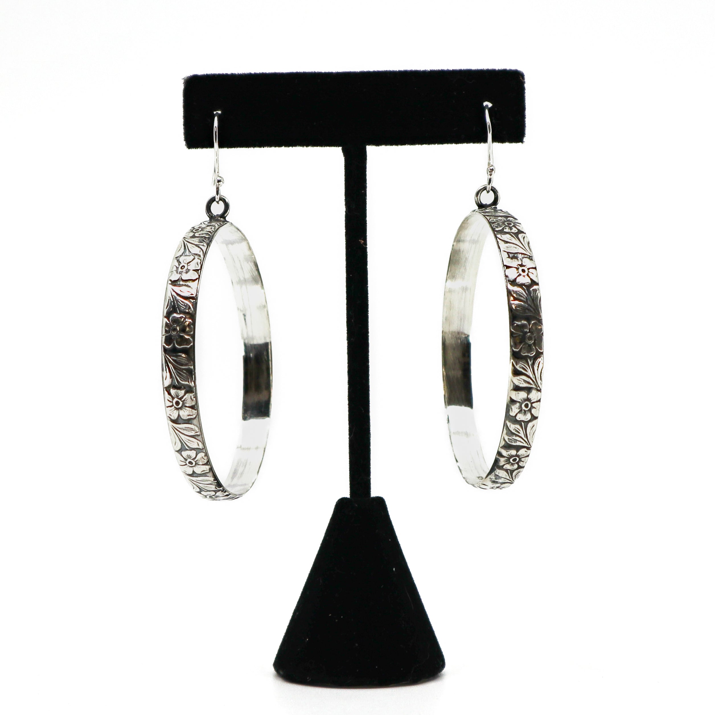 Handmade sterling silver floral hoop earrings on black stand