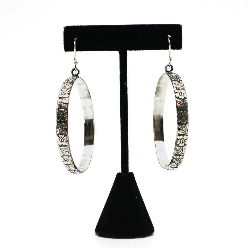 Handmade sterling silver floral hoop earrings on black stand