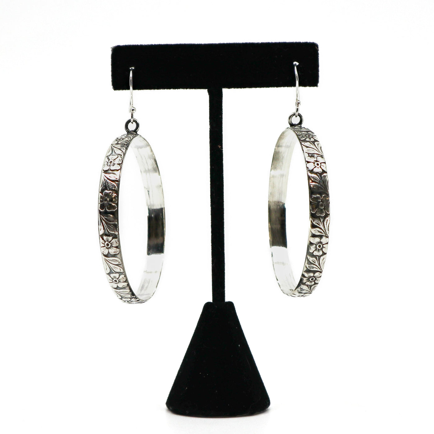 Handmade sterling silver floral hoop earrings on black stand