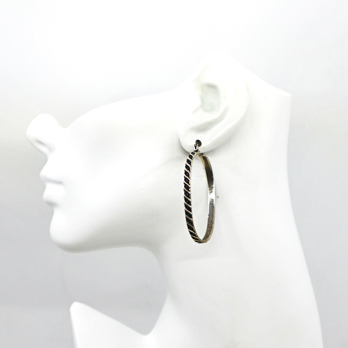 Handmade sterling silver oval hoop earring on white mannequin head