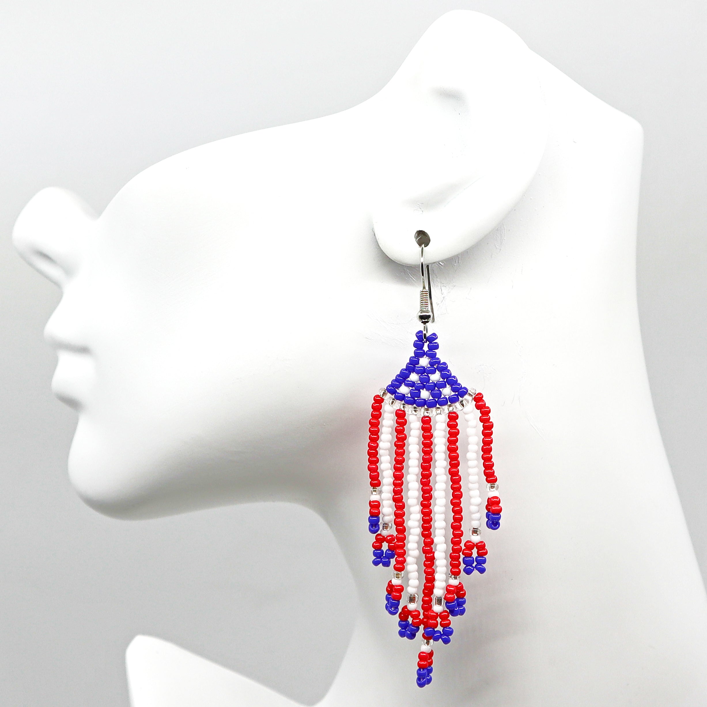 Boho USA flag beaded tassel earrings with red, white, and blue rice bead design on mannequin head.