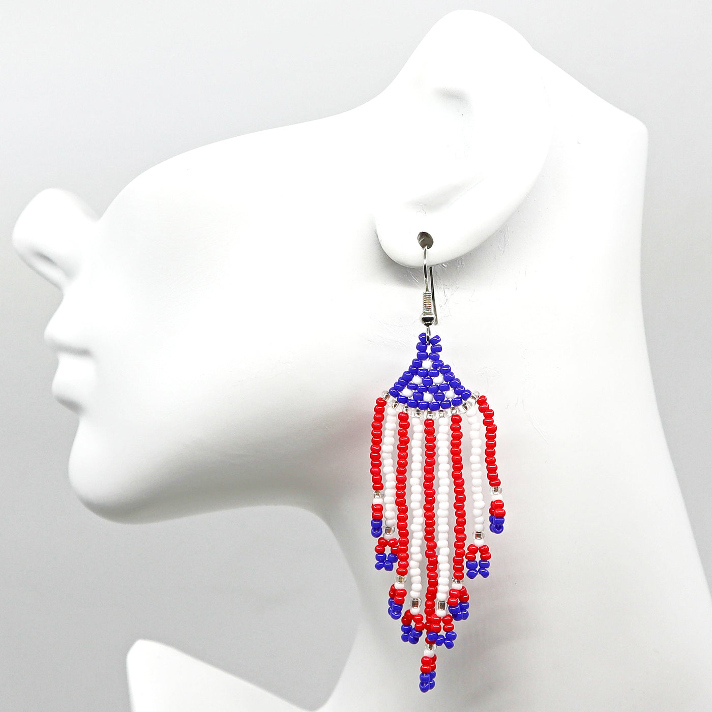 Boho USA flag beaded tassel earrings with red, white, and blue rice bead design on mannequin head.