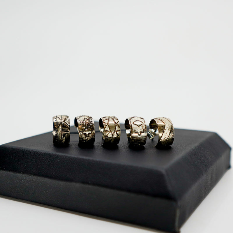Handmade sterling silver stamped mini hoop earrings with unique designs displayed on black box