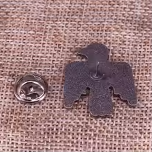 Vintage styled Thunderbird pin with crossed arrows motif on a burlap background.