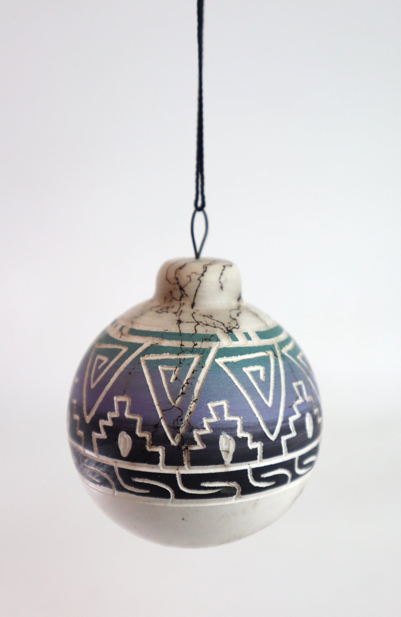 Navajo ornament with geometric patterns and hanging string.