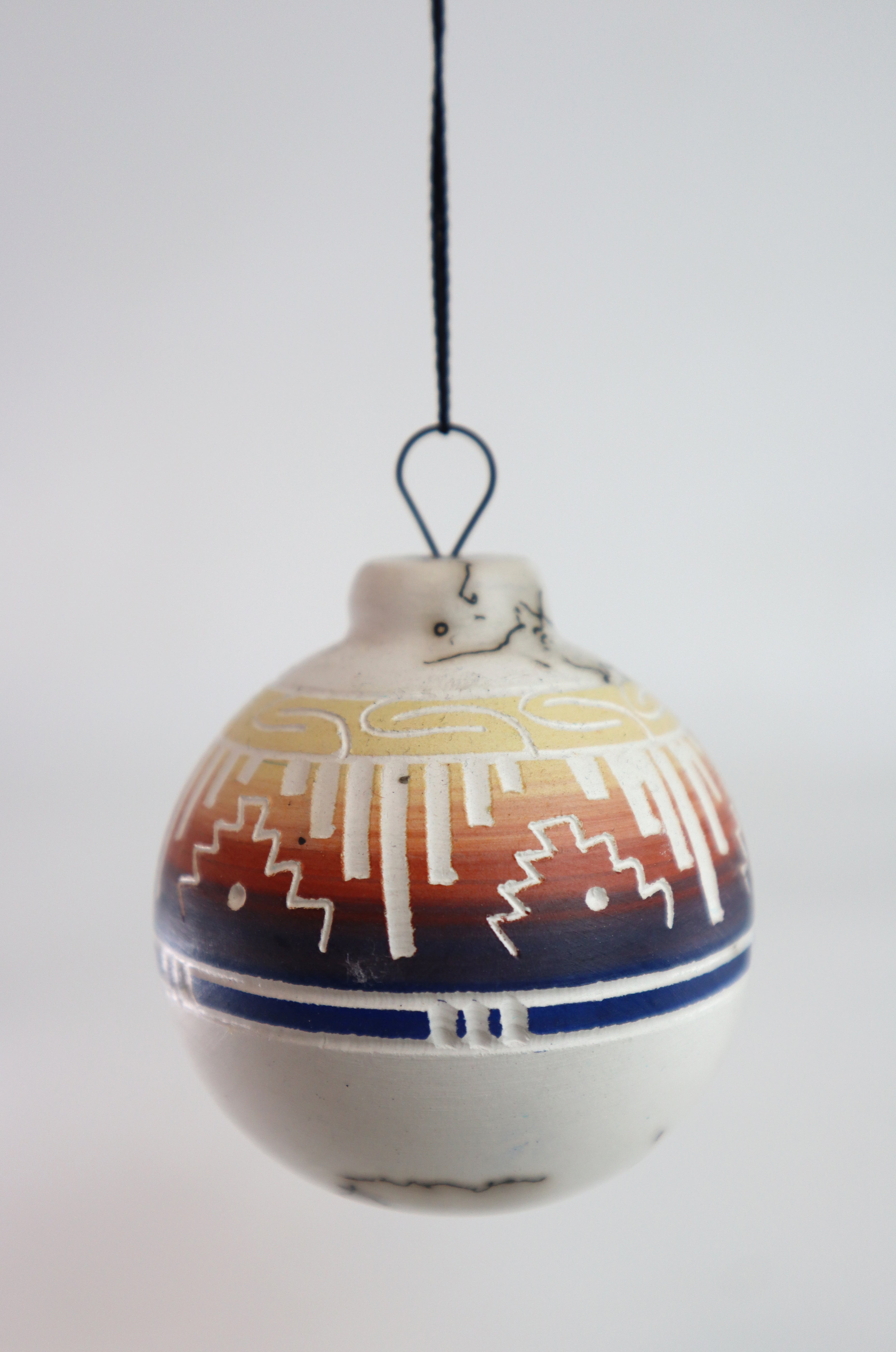 Navajo Ornament with traditional geometric design hanging on a string.