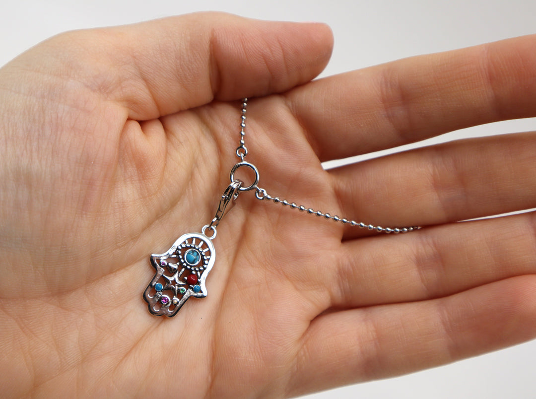 Sterling silver charm necklace with zircon gemstone held in a hand.