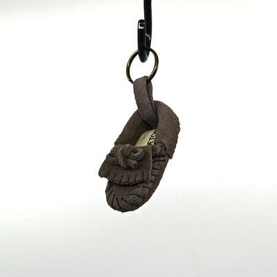 Minnetonka key ring shaped like a small brown suede moccasin hanging on a black hook