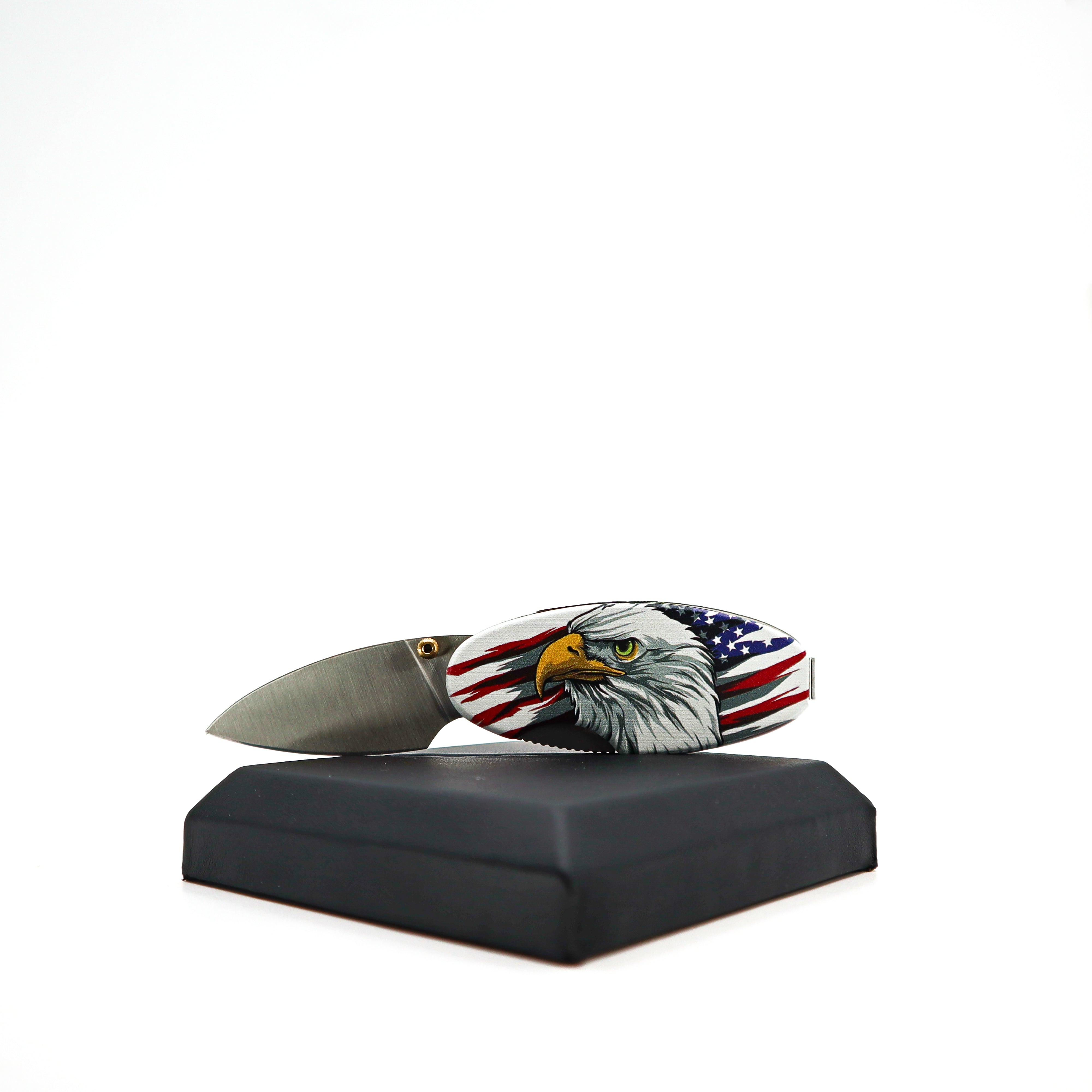 Compact Money Clip Linerlock knife with patriotic eagle design and stainless steel blade on black display stand