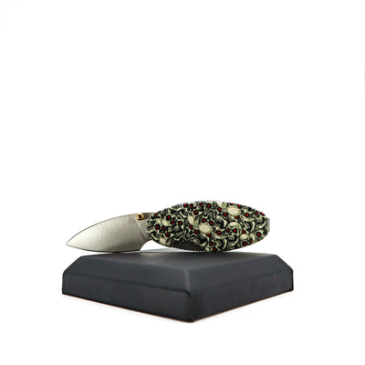 Compact Money Clip Linerlock knife with skull design handle and satin stainless steel blade on display stand