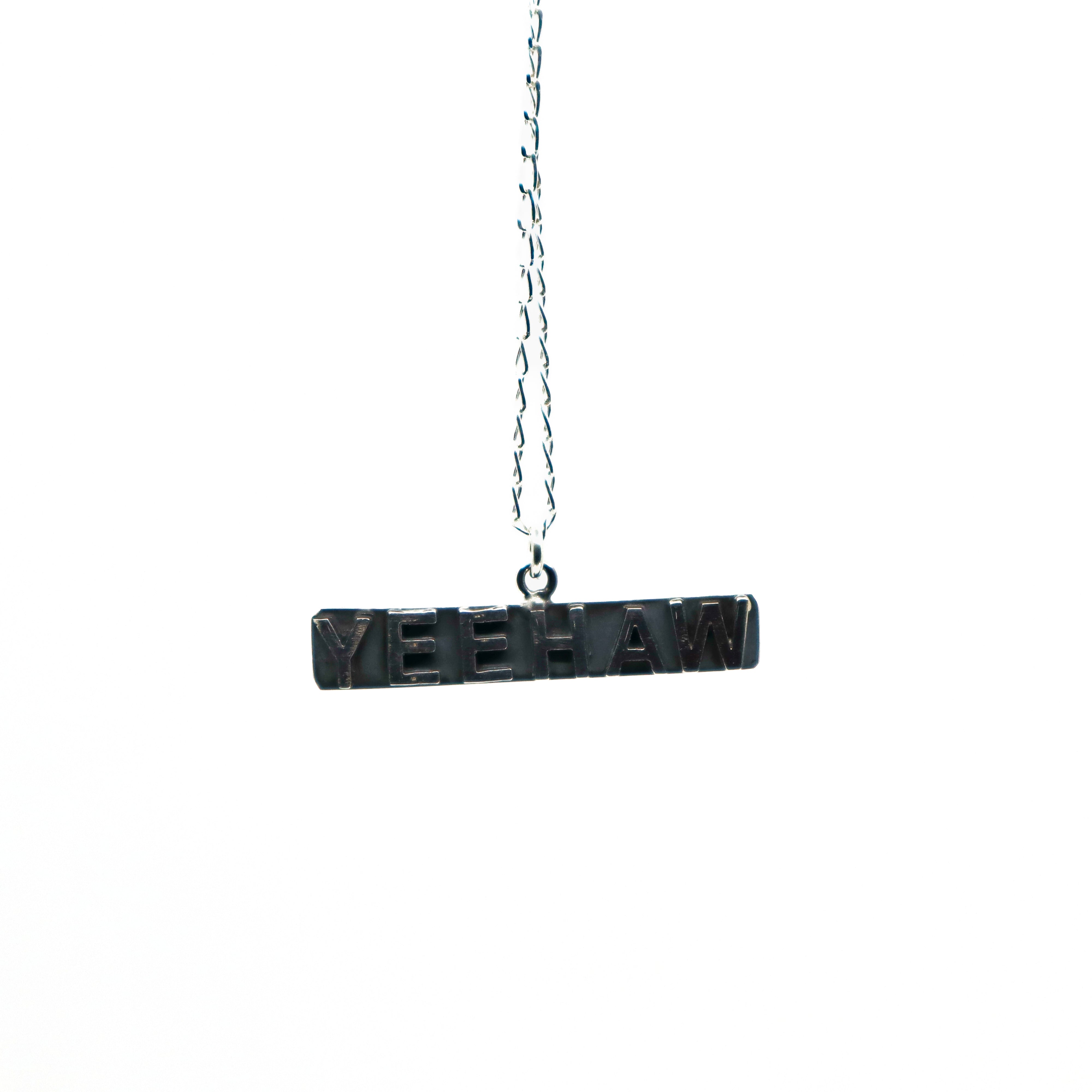 Handmade sterling silver Yeehaw necklace displayed on black stand