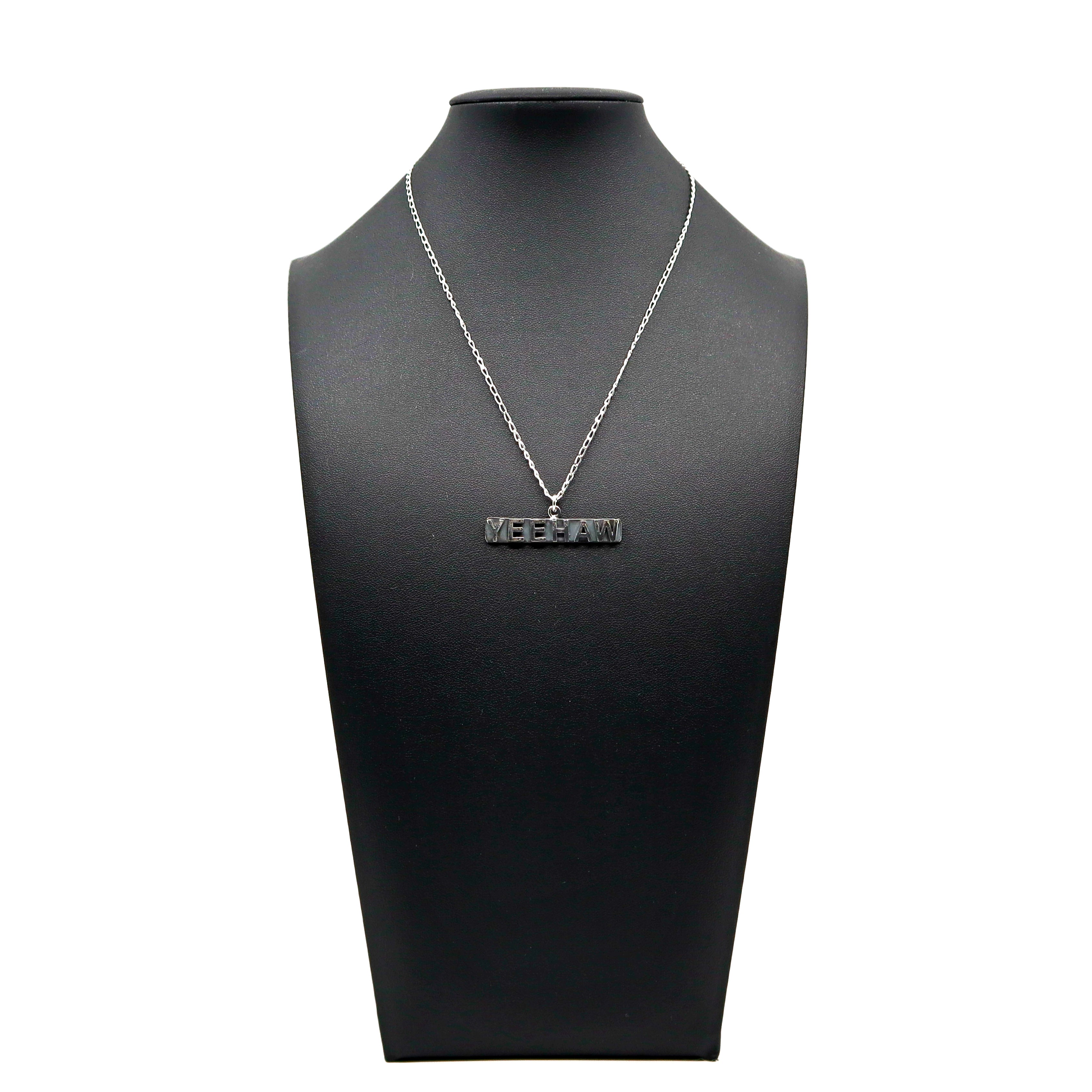 Handmade sterling silver Yeehaw necklace displayed on black stand