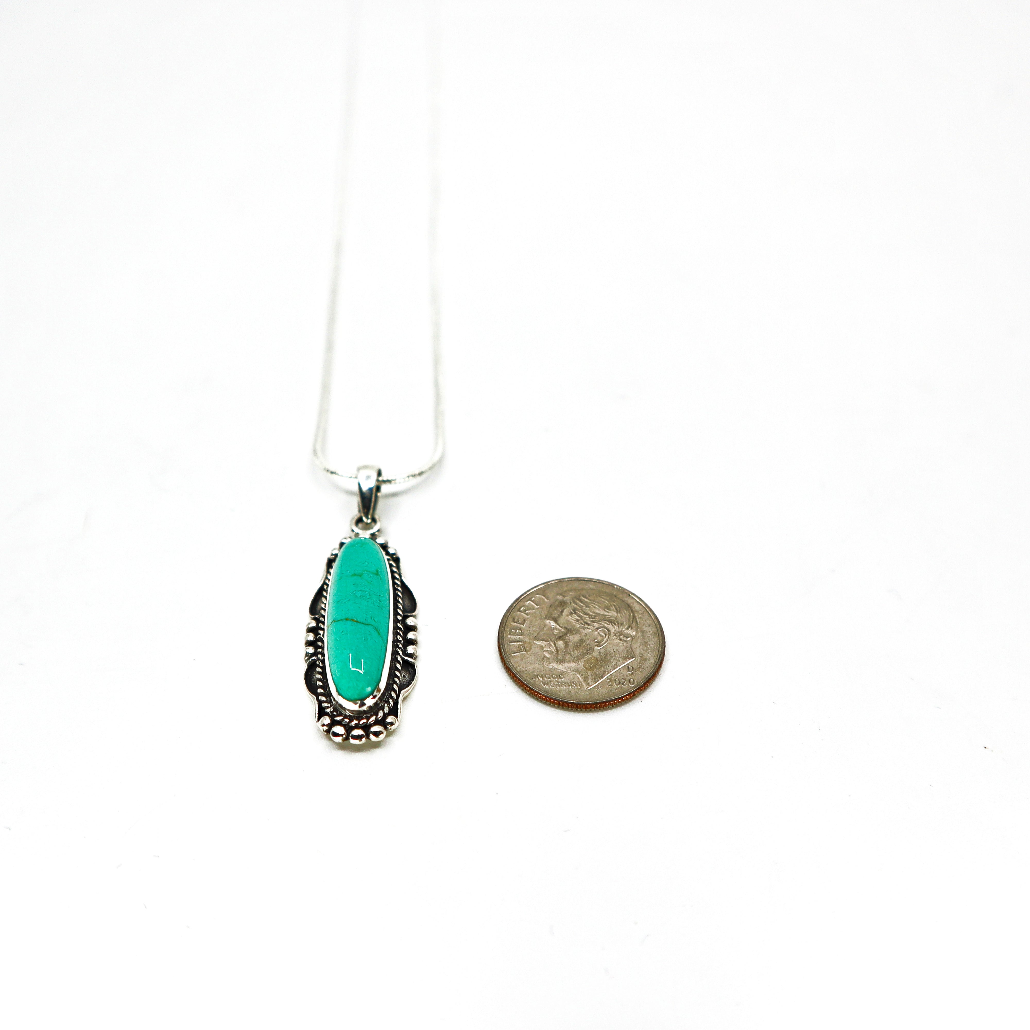 Sterling silver turquoise necklace pendant next to a dime for size comparison