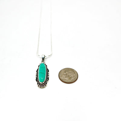 Sterling silver turquoise necklace pendant next to a dime for size comparison