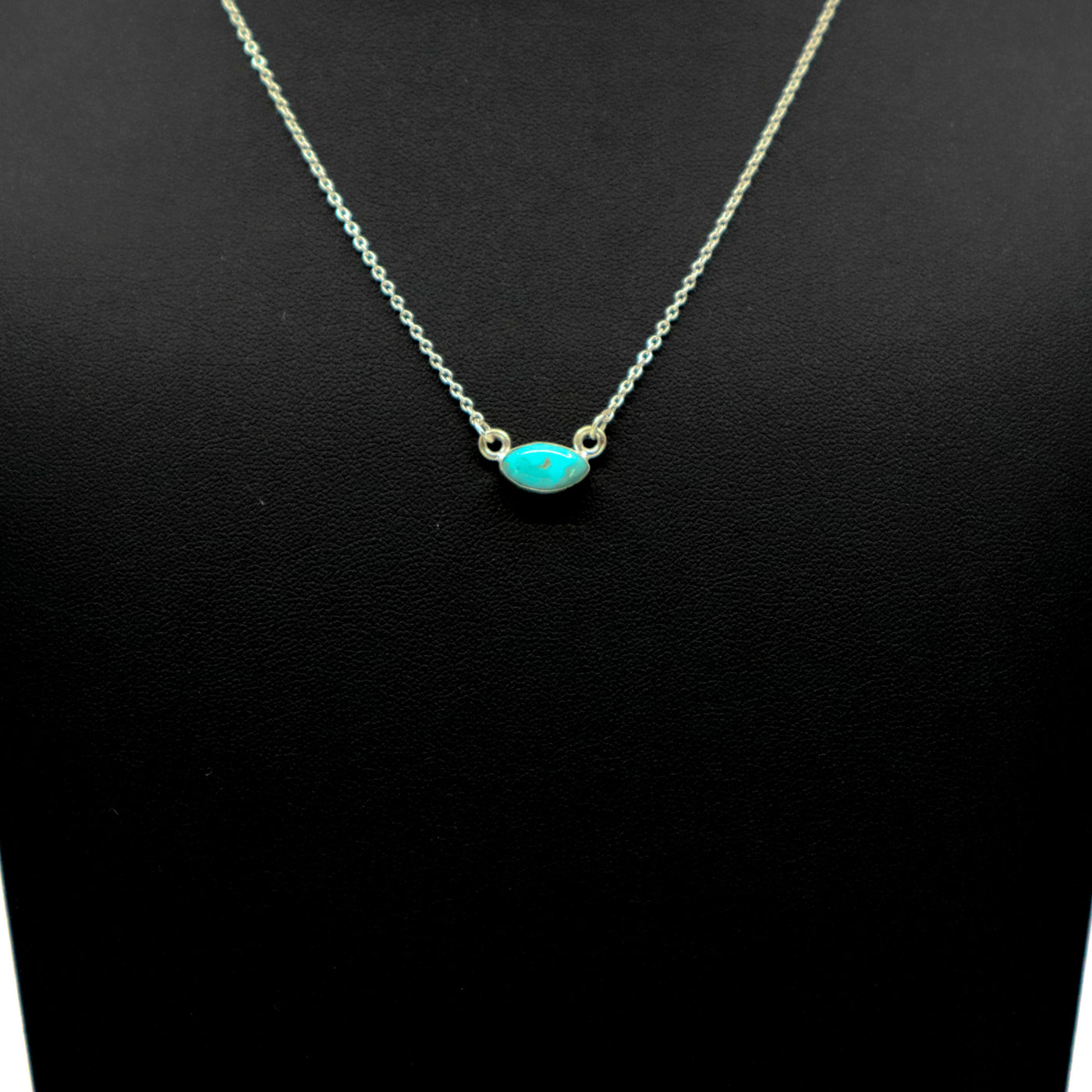 Handmade sterling silver necklace with oval turquoise pendant on black background